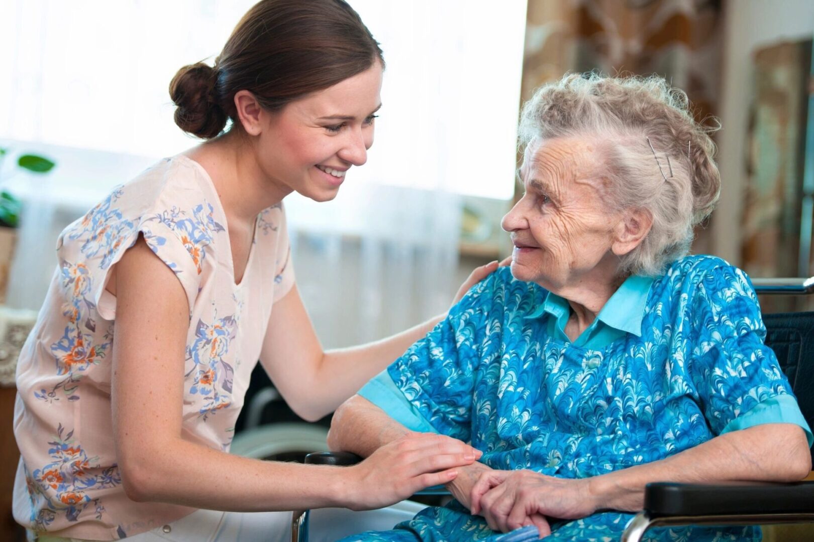 A woman holding the hand of an older person.